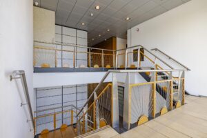 Trapruimte met modern metalen hekwerk en houten accenten in een kantoorgebouw aan de Joan Muyskenweg.